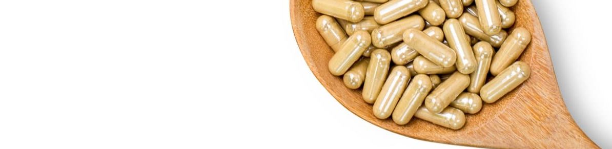 Kratom capsules on wood spoon